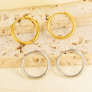 Detail of classic gold and silver stainless steel hoop earrings on stone surface