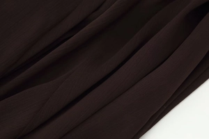 Close-up of pleated dark brown chiffon fabric showing fine texture and sheer quality