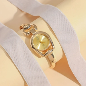 Macro detail of gold vintage button watch with roman dial and horseshoe buckle link