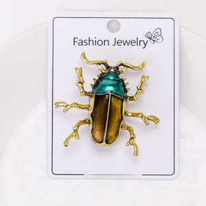 Detailed macro view of an alloy beetle brooch in gold and metallic green finish