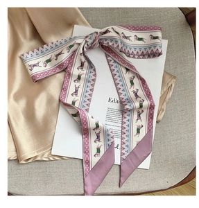Detail of elegant silk twilly scarf with horse patterns on champagne silk fabric background