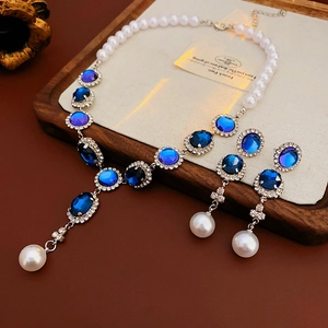 Dettaglio della collana di perle e orecchini con gemme blu su vassoio in legno