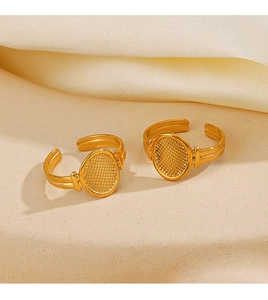 Close-up of golden geometric oval rings with grid texture on beige sandy background