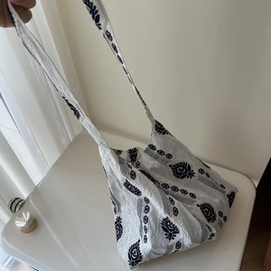 Close-up of ethnic blue floral embroidery on white linen cotton shoulder bag