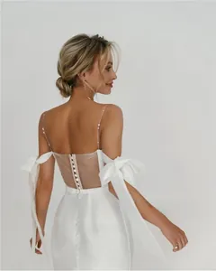 Detailed back view of white wedding dress with bow sleeves and button mesh back