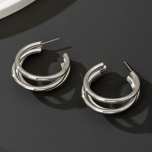 Macro shot of silver triple-layered C-shaped metal earrings with high-polish mirror finish