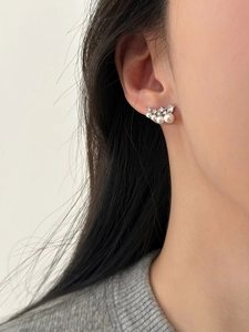 Close-up of elegant silver earrings with shimmering pearls and zircon on model ear