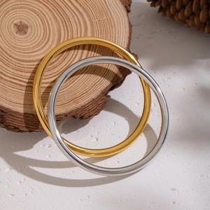 Detail of gold and silver minimalist round metal bangles displayed on a wooden base