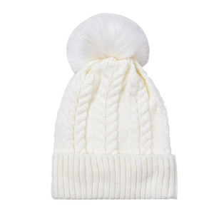 Détail d'un bonnet en tricot torsadé crème avec un grand pompon en fausse fourrure