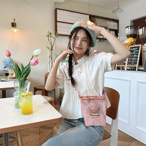 Detail of pink embroidered mini oxford bag with carousel motif and woven shoulder strap
