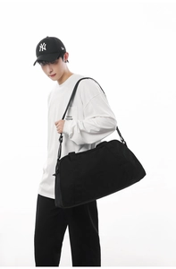 Asian male model showcasing a large black travel duffel bag for sports and gym use