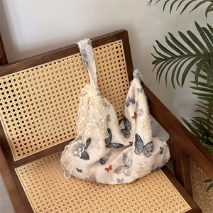 Detail of lace tote bag with butterfly print and floral ornaments on wooden chair