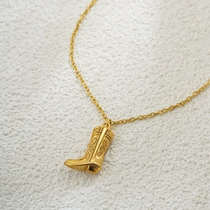 Macro shot of 18K gold plated stainless steel cowboy boot pendant with engraved details
