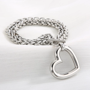 Detail of silver heart pendant bracelet with woven curb chain and toggle clasp closure
