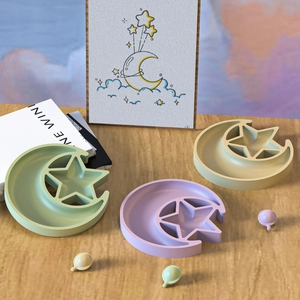 Pastel star and moon silicone molds for jewelry trays displayed on a wooden surface