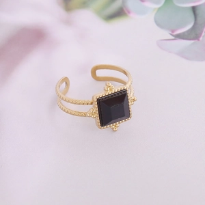 Détail d'une bague dorée réglable ornée d'une pierre noire carrée au style vintage