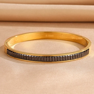 Macro detail of gold-plated stainless steel bangle with black inlay and S. Steel engraving
