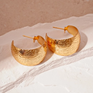 Detailed view of gold C-shaped earrings with unique embossed wavy metal texture