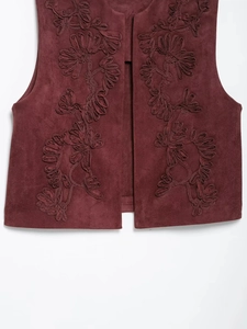 Dettaglio ravvicinato del ricamo floreale 3D su un gilet bordeaux in finta pelle
