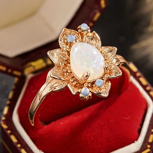 Dettaglio anello vintage a fiore dorato con opali su base di velluto rosso lusso