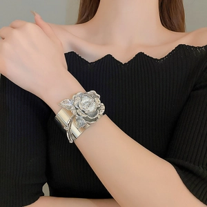 Detailed close-up of a silver metal open cuff bracelet featuring a large 3D rose flower