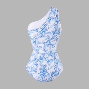 Detail of blue tropical leaf pattern and ruched texture on one-shoulder swimsuit