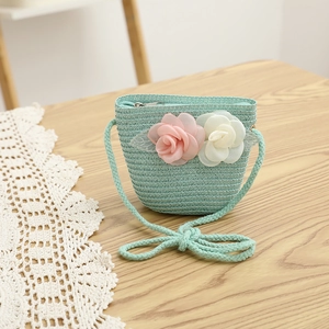 Detail of mint green straw woven crossbody bag with 3D fabric flowers for children