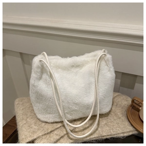 Close-up of white faux fur shoulder bag texture with long straps on warm knit scarf