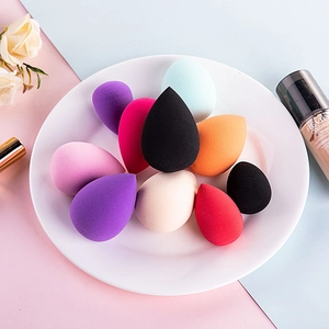 Macro shot of multi-colored teardrop makeup sponges on a ceramic tray with floral decor