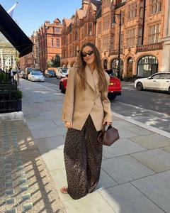 Close-up of khaki oversized double-breasted blazer styled with leopard print wide-leg pants