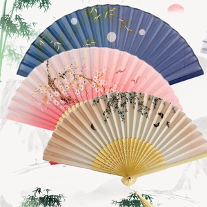 Detailed view of three traditional Chinese silk fans with bamboo, cherry, and floral patterns