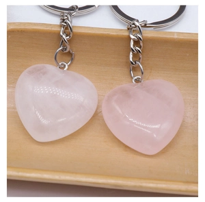 Macro shot of two polished heart-shaped pink crystal keychains on a wooden tray
