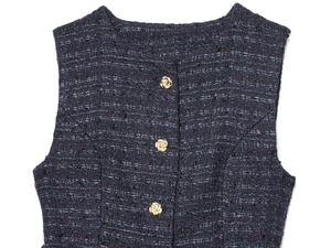 Détail de la texture du tweed et boutons roses dorés décoratifs sur un gilet sans manches