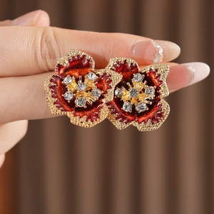 Close-up of vintage flower earrings with dark red enamel petals and crystal center