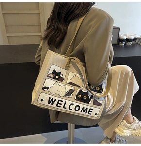 Detail view of canvas cat tote bag with Welcome print on a shoulder-carried model