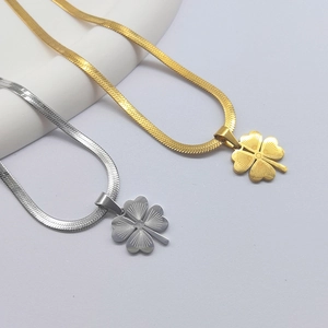 Golden and silver four-leaf clover necklaces with herringbone snake chains on gray background
