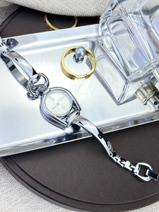 Detail view of a vintage silver quartz watch on a decorative tray with elegant jewelry