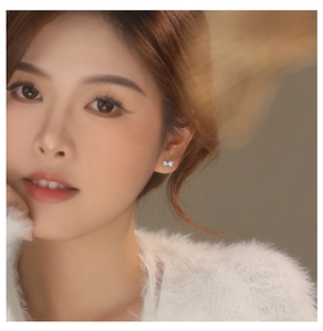 Close-up of elegant S925 silver bow stud earrings with sparkling cubic zirconia on ear