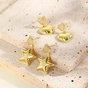 Elegant gold heart and star dangle earrings with pavé zircon accents on stone surface