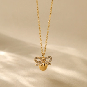 18K gold plated bow and heart pendant necklace with zircon inlay on beige fabric