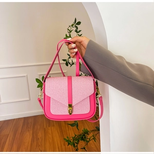 Detail of fuchsia saddle bag with woven texture flap and gold metal clasp hardware