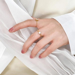 Detail of two 18K gold plated titanium rings with round cubic zirconia on a soft white fabric