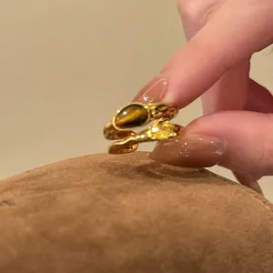Close-up of vintage gold rings set with tiger eye and amber stones on textured fabric