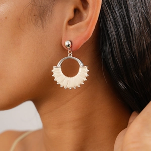Close-up of a model wearing a silver geometric round earring with beige leather details