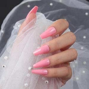 Glossy pink ballerina press-on nails shown on hand holding pearl accessories