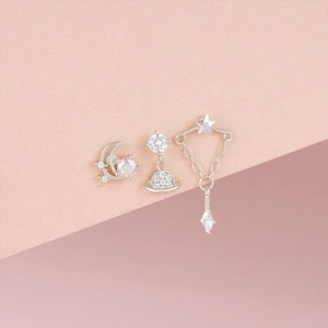 Detailed view of three silver S925 moon, star, and planet stud earrings with gemstones