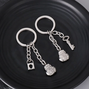 Detail view of silver stainless steel fortune bag and lock pendant keychains on a black base