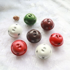 Close-up of 5cm Christmas star cutout bells in festive colors on a white plush surface