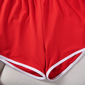 Detail of red athletic shorts with white hem binding showing high-quality fabric texture
