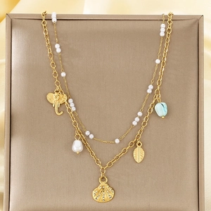 Détail du collier doré double couche avec breloques coquillage et perles sur soie